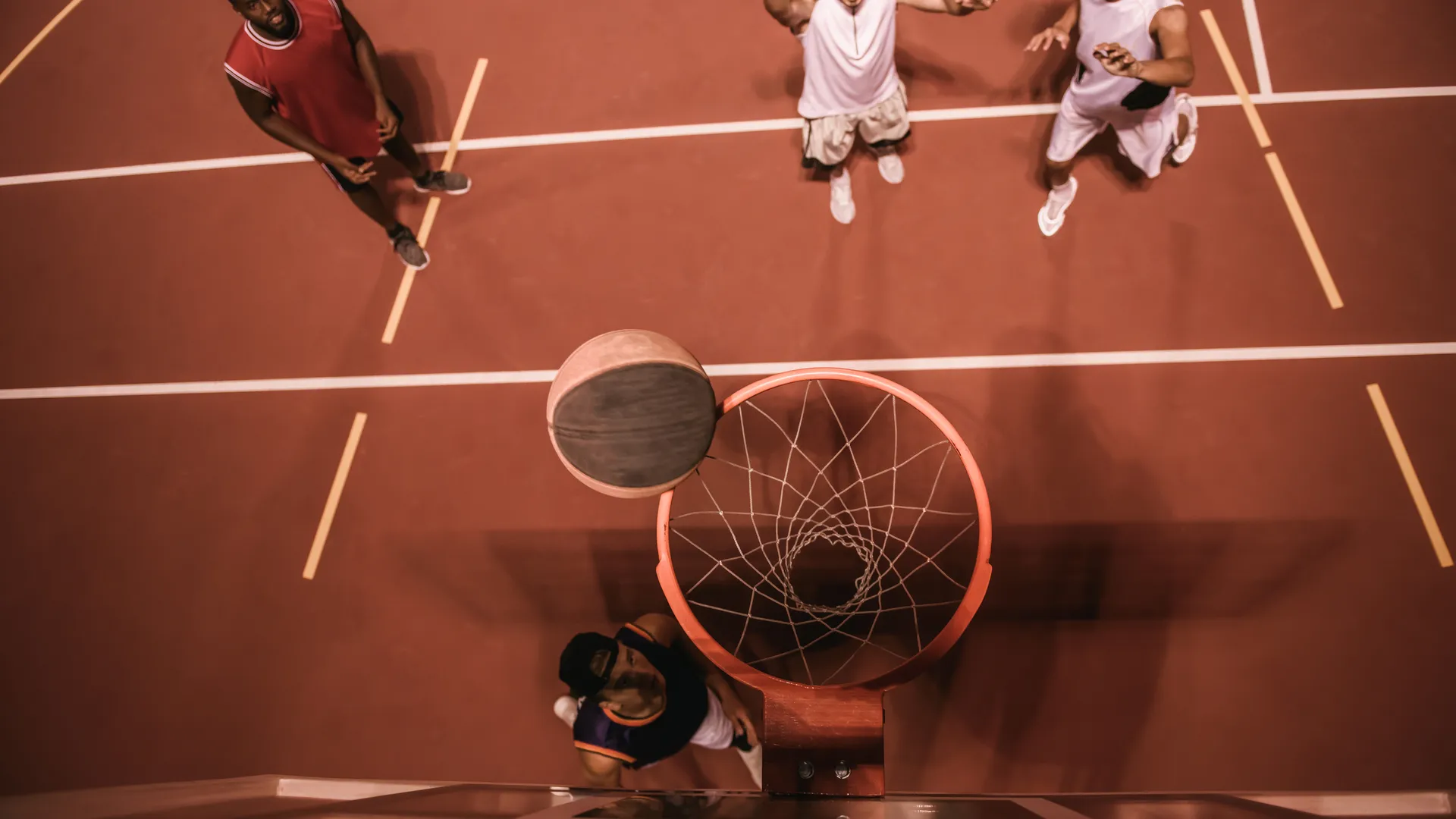 Basketball players around the hoop during live game action.