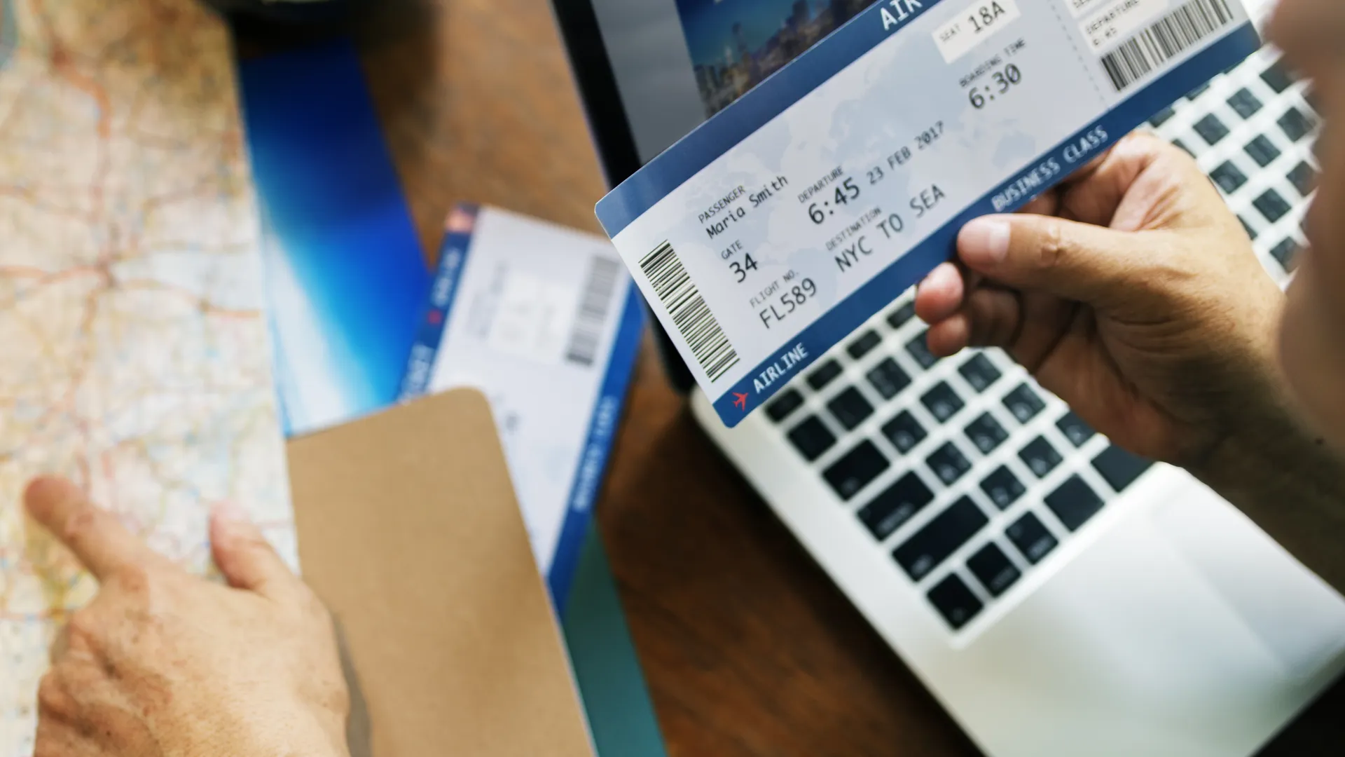 Laptop, map, and airline tickets for DIY versus all-inclusive sports travel planning
