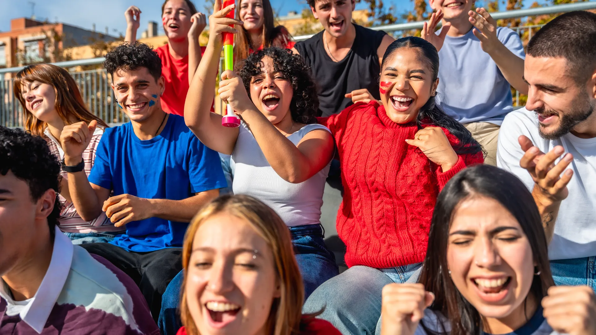 Group of friends cheering together in stadium seats for a sports trip planning guide.