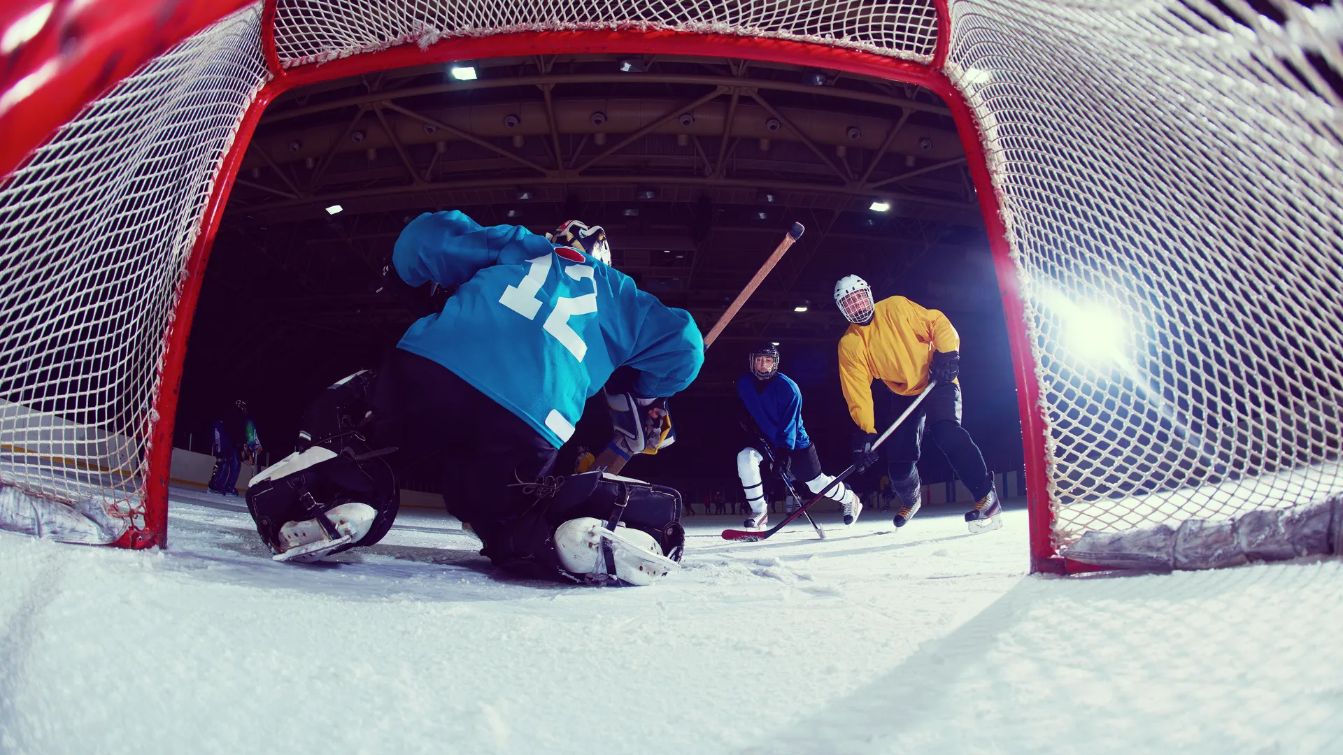 Ice hockey game action viewed from inside the goal for a hockey fan trip guide.