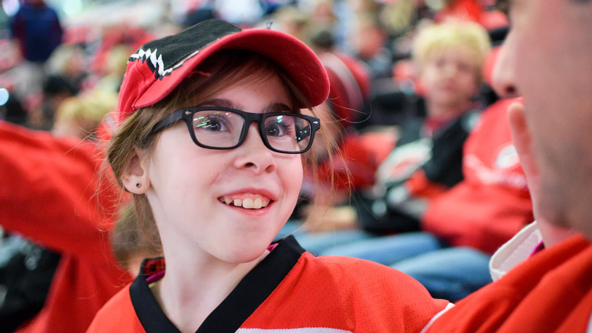 Young hockey fan in a red jersey sitting in arena stands
