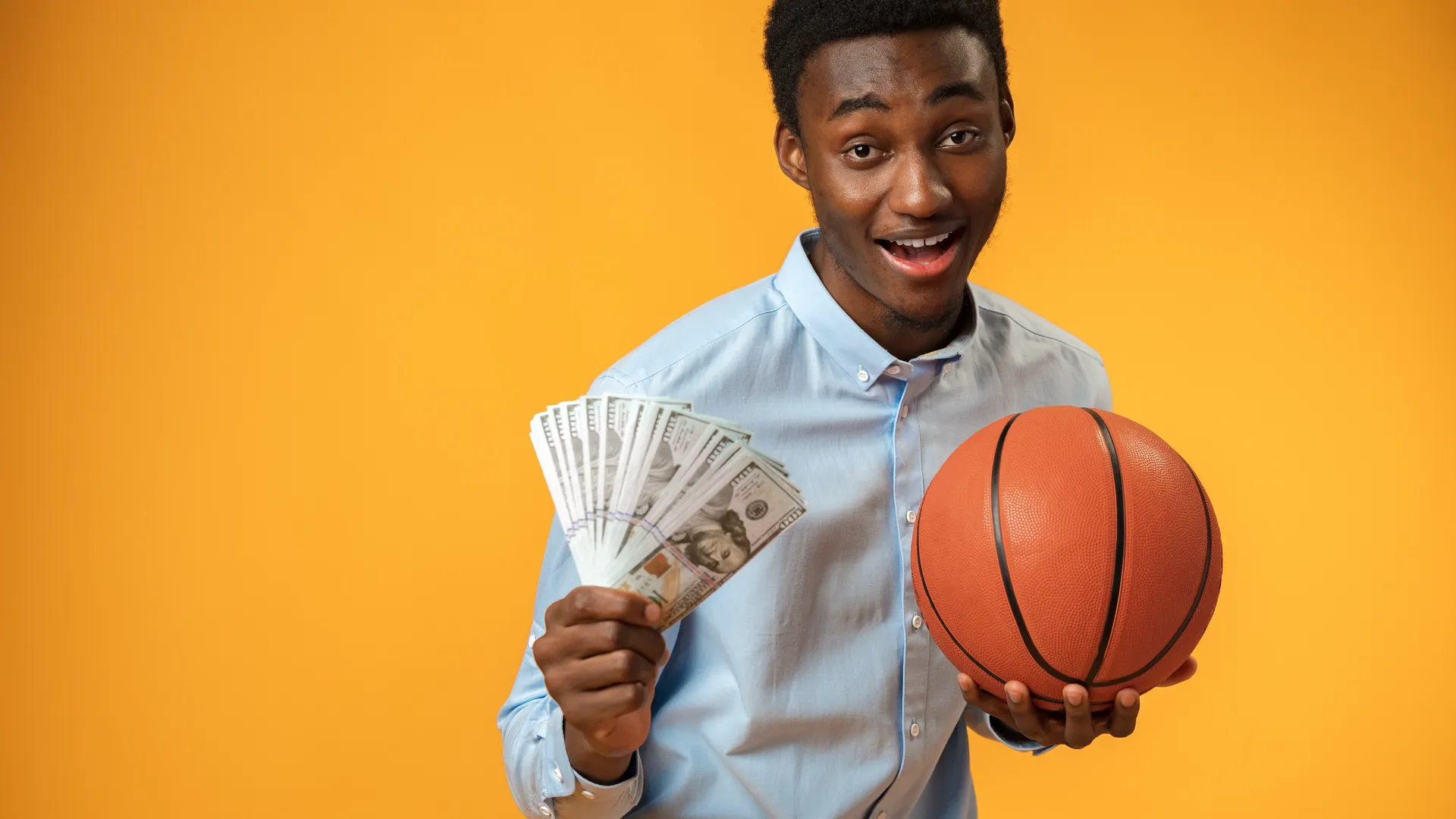 Basketball fan holding cash for a March Madness budget travel guide.