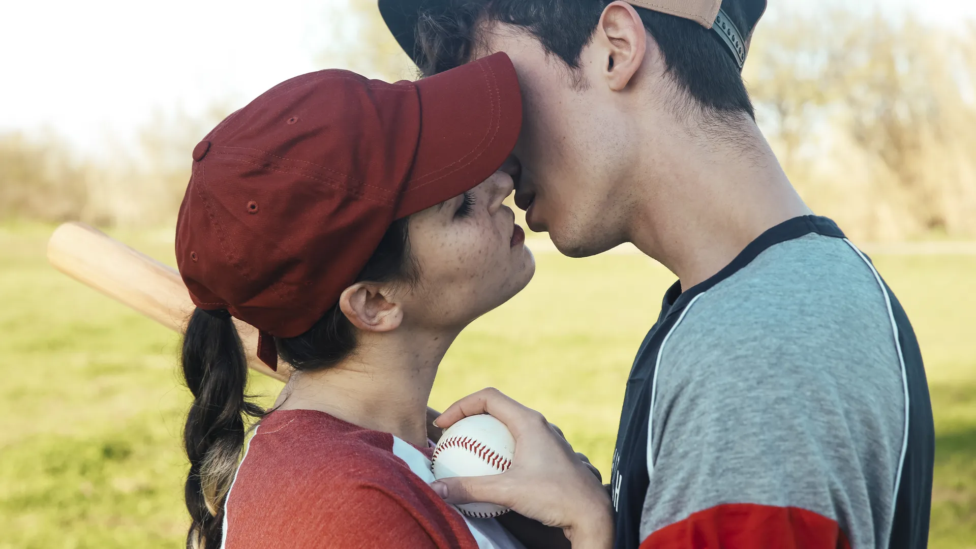 Couple with baseball equipment for an MLB ballpark date night guide.