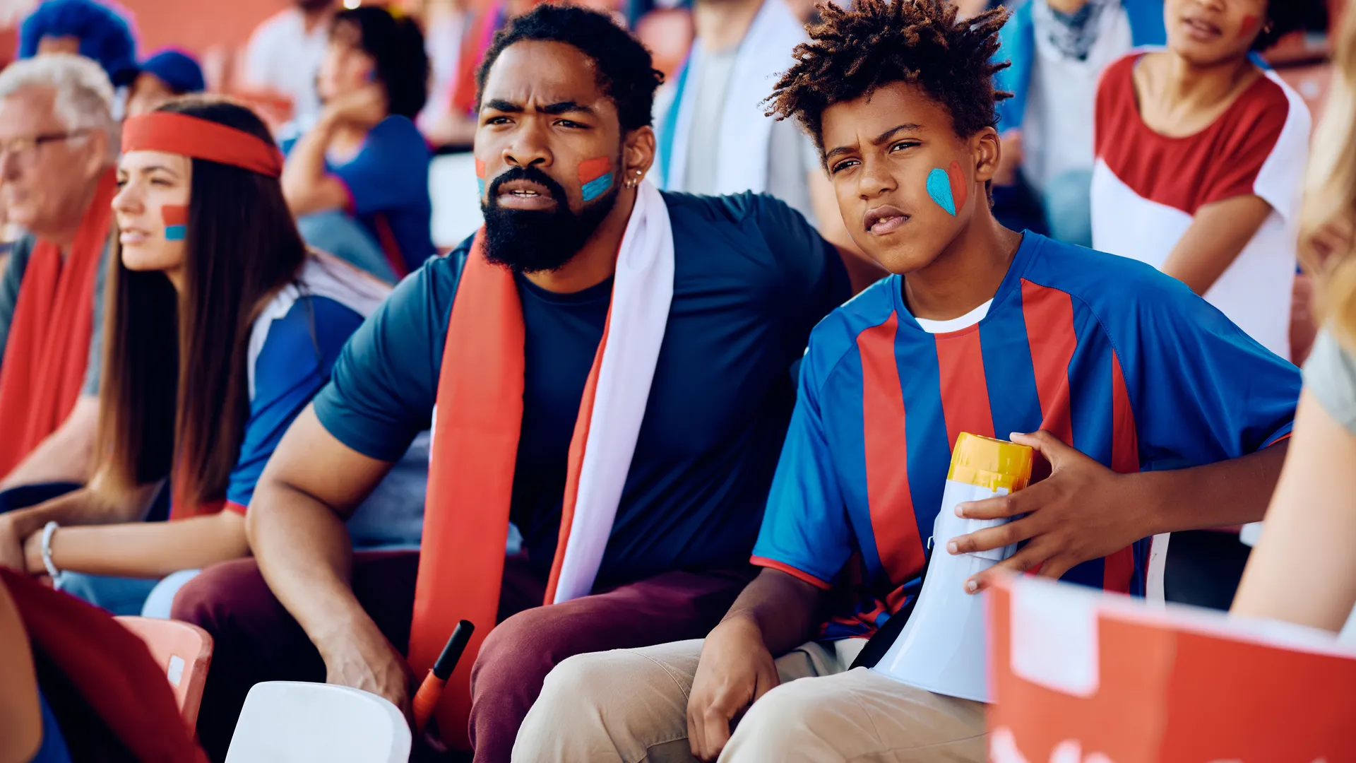 Father and son watching a preseason football game from stadium seats
