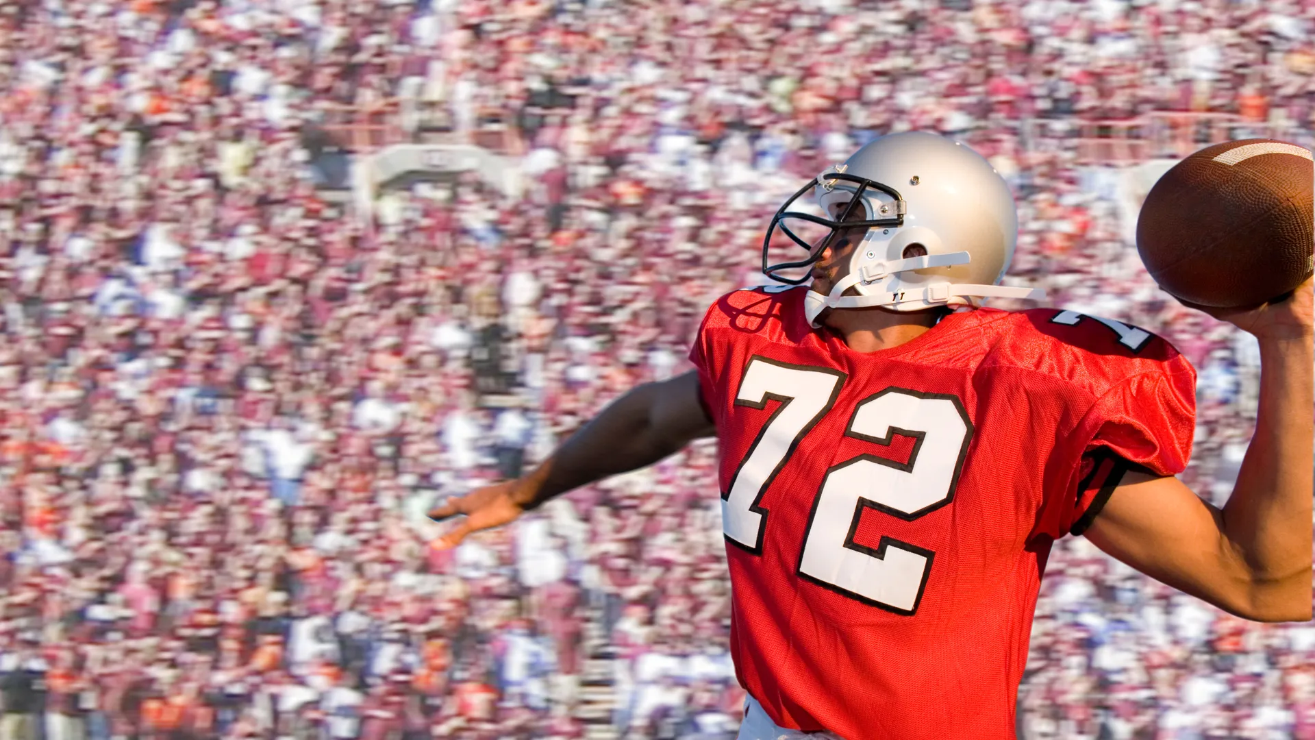 Football quarterback throwing a pass in a crowded stadium