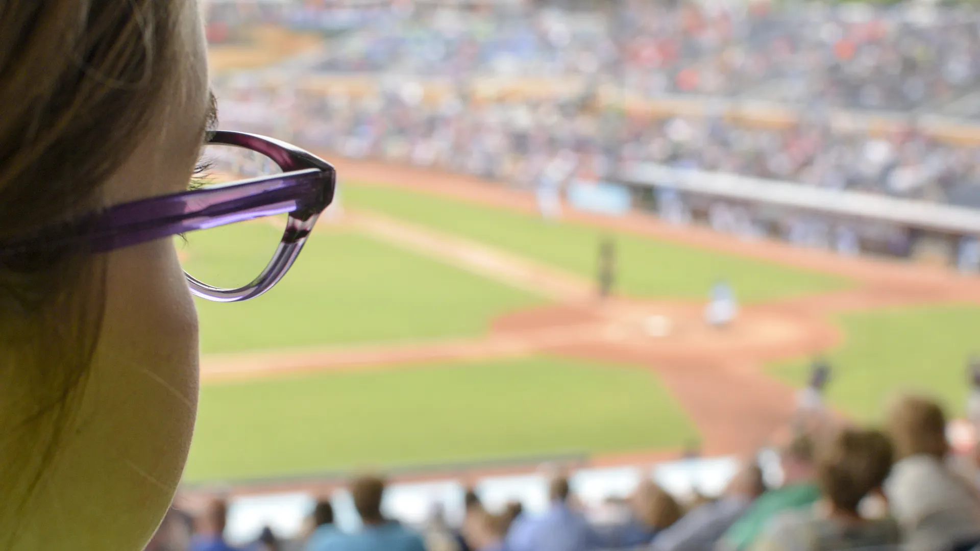 Spectator watching a sunny baseball game for a spring sports travel calendar.