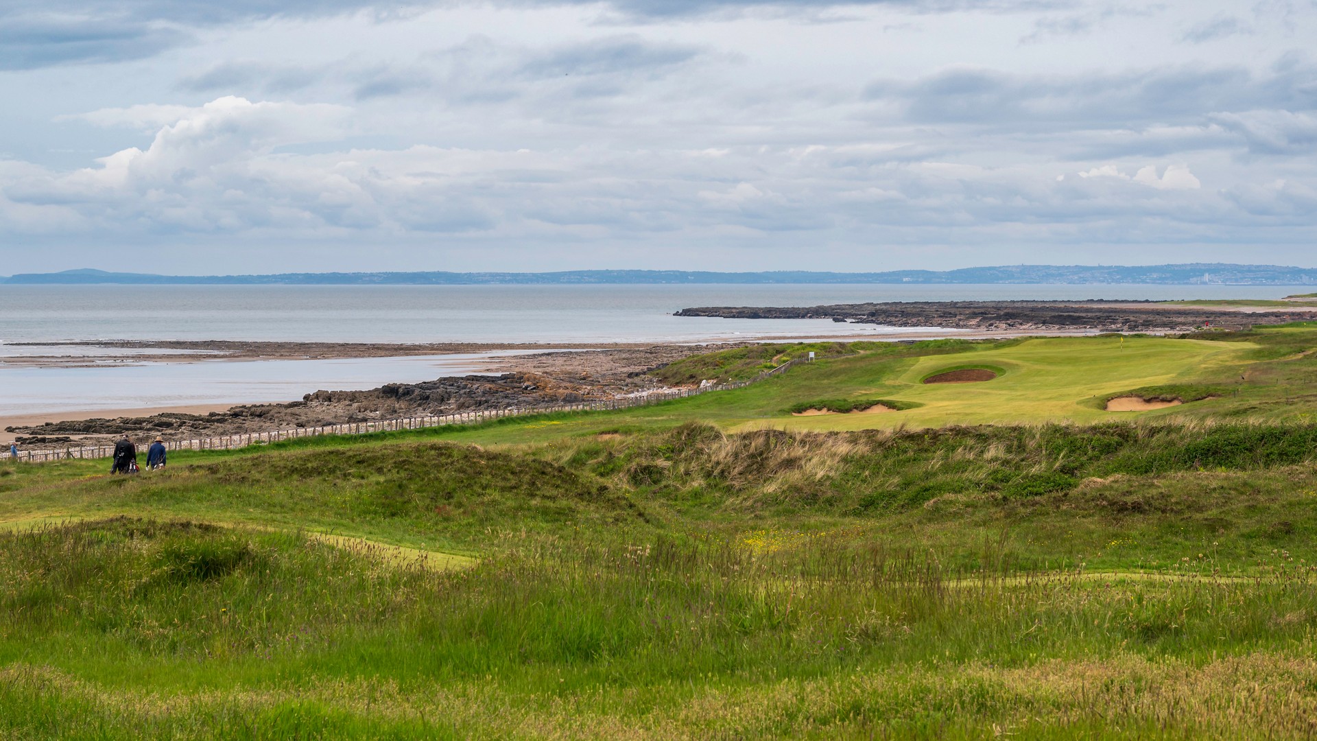 A coastal links golf fairway in the United Kingdom with bunkers and a distant green, evoking the pre-tournament hush before The Open Championship at Royal Birkdale.