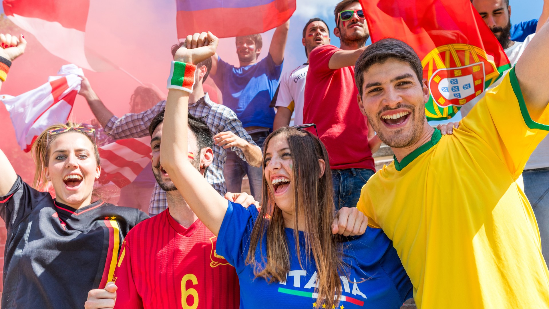Diverse soccer fans cheering with national flags at a knockout-round tournament match